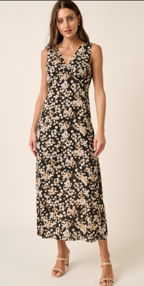 This is a full length image of a model. She is wearing a sleeveless black dress with a floral pattern in cream. The dress comes down to her mid calves. The dress has a v neckline.