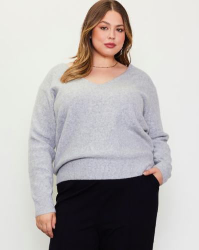 This model is wearing a long sleeve grey sweater. The neckline is a rounded v shape.