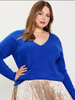 This model is wearing a long sleeve sweater in cobalt blue. The neckline is a rounded v shape.